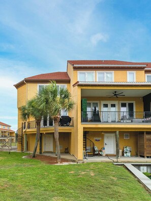 A two-story building with a balcony, a pool, and a palm tree in the foreground.