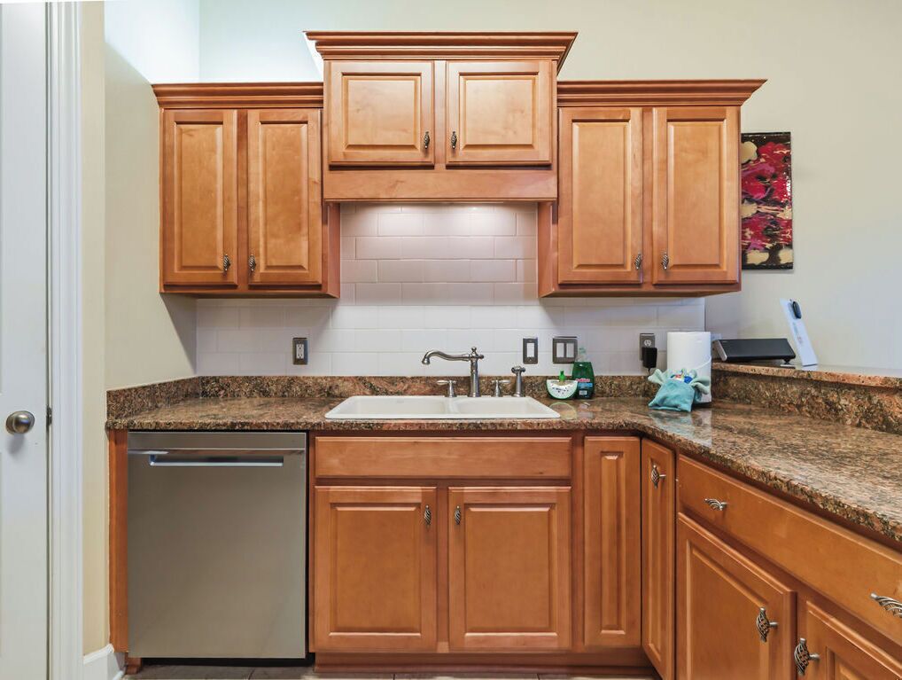 A kitchen with wooden cabinets, a stainless steel dishwasher, and a granite countertop.