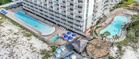 A high-rise hotel with multiple balconies, a central swimming pool, and a separate pool area.