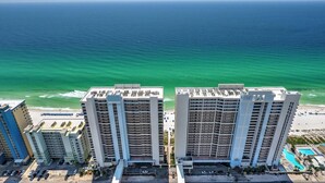 Un hôtel de grande hauteur doté de nombreux balcons offrant une vue sur une plage et l’océan.