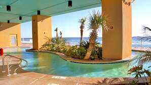 Une piscine à l’eau d’un bleu cristallin, entourée de palmiers et offrant une vue sur l’océan.