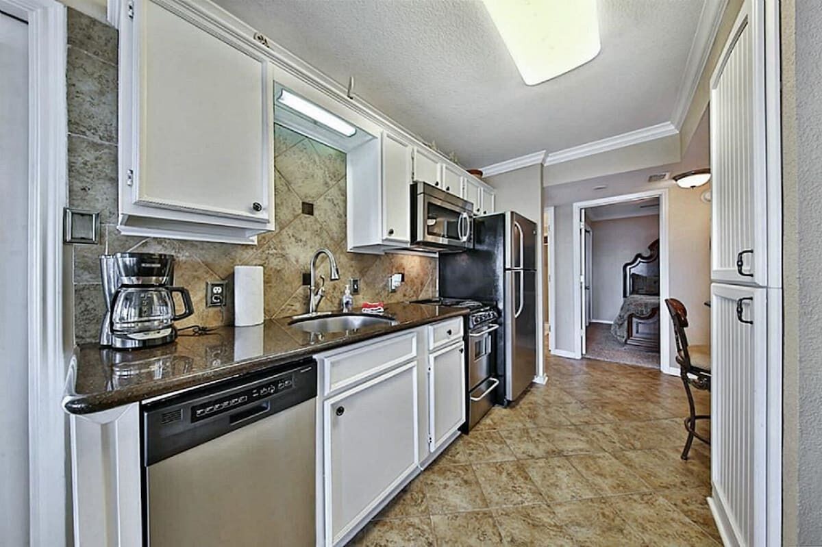 A kitchen with white cabinets, a dishwasher, a microwave, and a refrigerator.