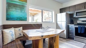Une cuisine moderne avec une table en bois, un banc avec des coussins et une grande fenêtre.