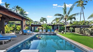 Une piscine avec des chaises longues et des palmiers.