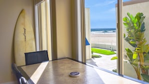 Ein Zimmer mit Blick auf den Strand, ein Surfbrett, das an der Wand lehnt, und eine Pflanze auf dem Fensterbrett.