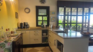 A kitchen with a coffee maker, a sink, and a window with a view of greenery. - PREMIER HOST Private 3 bdrm, 1600 sq ft Fully Air-Conditioned villa in Blue Bay (Sint Michiel)