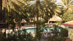 A pool area with palm trees, lounge chairs, and a thatched umbrella. - PREMIER HOST Private 3 bdrm, 1600 sq ft Fully Air-Conditioned villa in Blue Bay (Sint Michiel)