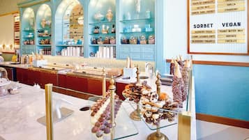 Un glacier proposant une grande variété de parfums de crème glacée et de sorbets, présentés sur des étagères, ainsi qu’un tableau affichant le menu.