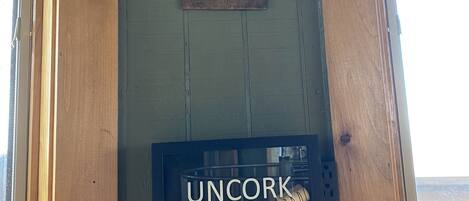 A wooden wall with a cork and wine rack, and a framed sign with 'Uncork & Unwind' text.
