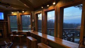 A wooden bar area with benches and a TV screen.