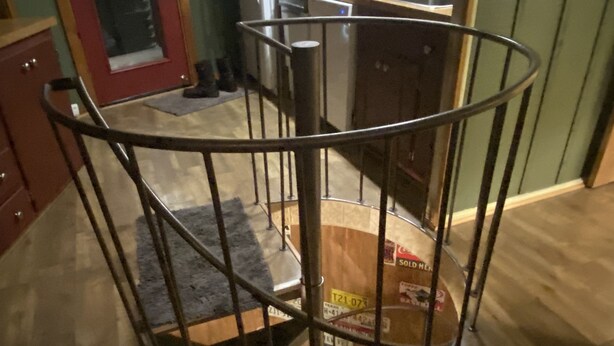 A spiral staircase with metal railings, wooden steps, and a rug on the floor.