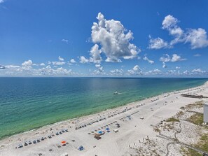 A beach with rows of umbrellas and beach chairs, a clear sky, and the ocean.