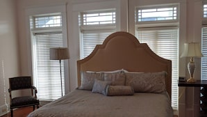 A bedroom with a large bed, a chair, a desk, and a ceiling fan. - Bright and Airy, Historic Condo on Monterey Square (Savannah)