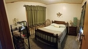 Une chambre avec un lit en bois, une table de chevet, une chaise et un étagère en métal.