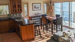Una cocina moderna con una isla grande, armarios de madera y un comedor con vista al océano.