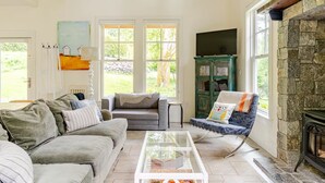 Una sala de estar acogedora con una chimenea de piedra, un sofá, un sillón y una mesa de centro.