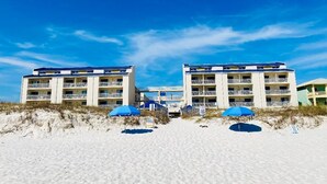 A beachfront hotel with multiple balconies and a sandy beach in the foreground. - August Dates Still Available This Summer - Enjoy this Comfy 3 Bedroom Unit! (Orange Beach)