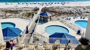 A poolside area with lounge chairs and umbrellas, a beach in the background, and a clear sky. - August Dates Still Available This Summer - Enjoy this Comfy 3 Bedroom Unit! (Orange Beach)