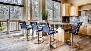 A kitchen with a bar area, large windows, and wooden cabinets.