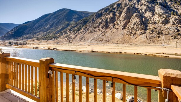 A wooden deck overlooking a river with mountains in the background.