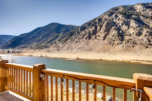 A wooden deck overlooking a river with mountains in the background. - Upscale Spectacular Mountain Retreat On The Lake In Georgetown Colorado (Georgetown)