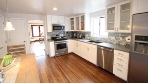 Una cocina moderna con armarios blancos, electrodomésticos de acero inoxidable y suelo de madera.