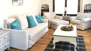 Una sala de estar con un sofá, dos sillones, una mesa de centro y una alfombra.