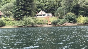 Une maison située au bord d’un lac, entourée d’une forêt dense.