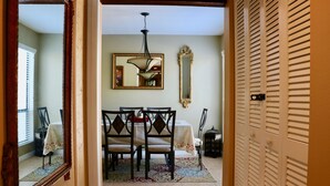 Un comedor con una mesa, sillas, una araña, un espejo y un tapete estampado.