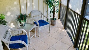 Un patio cubierto con mobiliario de mimbre y plantas en macetas.