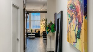 Un couloir moderne agrémenté d’un téléviseur à écran plat, d’un tableau abstrait aux couleurs vives et d’une plante décorative.