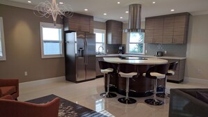 Una cocina moderna con una isla central, electrodomésticos de acero inoxidable y una zona de asientos tipo barra.