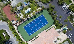 An aerial view of a tennis court surrounded by palm trees and a parking lot. - VILLA RENAISSANCE 603,1BR located Grace Bay. Easter weekend special. (Grace Bay)