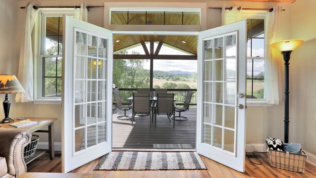An open door leading to an outdoor deck with a table and chairs, a lamp, and a basket on the floor. - Riverfront home on South Holston River Perfect for Fishing, Hiking, Relaxing (Bristol)