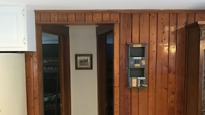 Une pièce avec des lambris en bois, une porte blanche et une petite étagère sur laquelle sont posés divers objets.