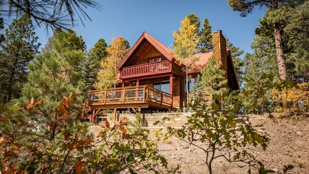 A cabin with a wooden deck and a large chimney, surrounded by trees. - Hot Tub, Hike, Fish, Ride, Eat, Drink or just relax in the Spa (Pagosa Springs)