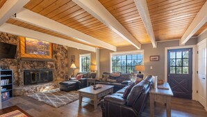 A spacious living room with a stone fireplace, leather sofas, and a wooden ceiling. - Hot Tub, Hike, Fish, Ride, Eat, Drink or just relax in the Spa (Pagosa Springs)