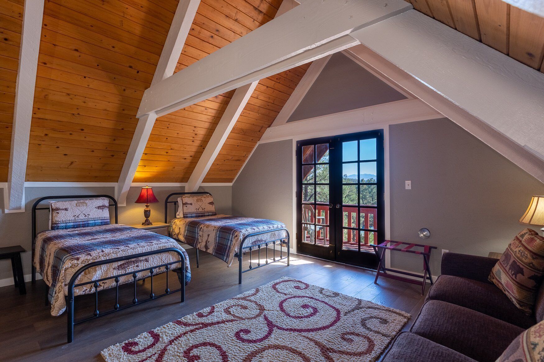 Une chambre confortable située sous les toits, avec deux lits, un canapé et une grande fenêtre.