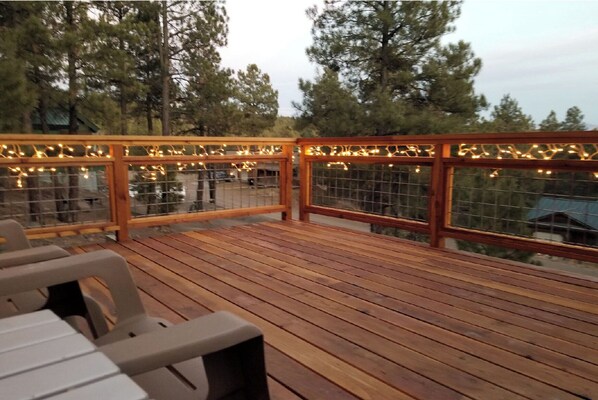 Relax on the deck surrounded by tall trees, with comfortable seating for a peaceful retreat.