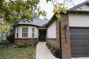 Une maison d’habitation avec un garage, une porte d’entrée et un chemin menant à l’entrée.