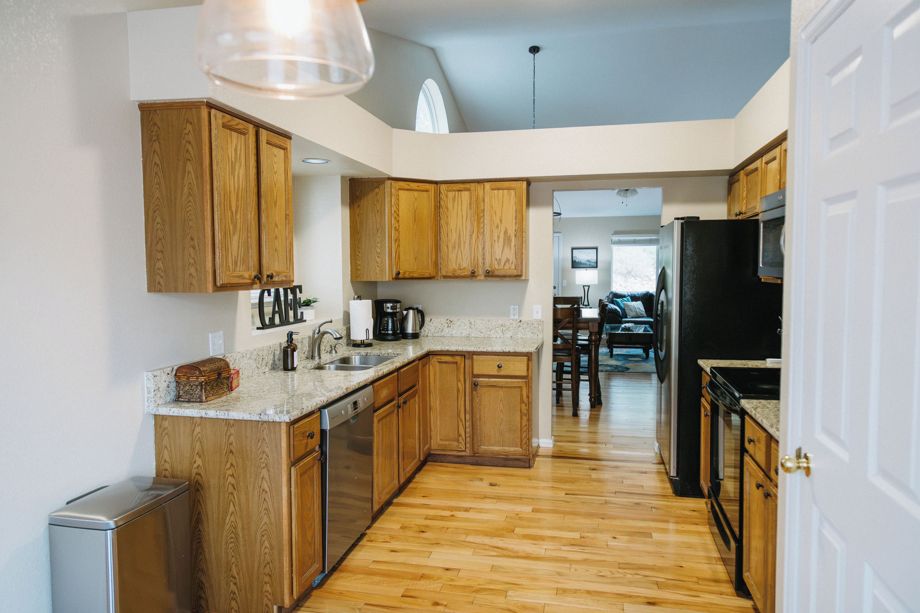 A kitchen with wooden cabinets, a stainless steel dishwasher, and a black refrigerator.
