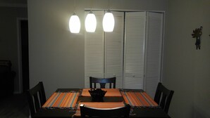 Una mesa de comedor con un camino de mesa colorido, sillas negras y un bol negro en el centro.