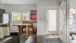 A modern kitchen with a refrigerator, wooden table, and a view of the outdoors through a window. - Villa 8 (Kihei)