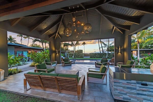 An outdoor lounge area with seating and a pool view. - Villa 8 (Kihei)