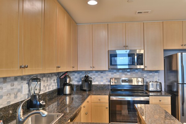 A modern kitchen with wooden cabinets, stainless steel appliances, and a granite countertop.