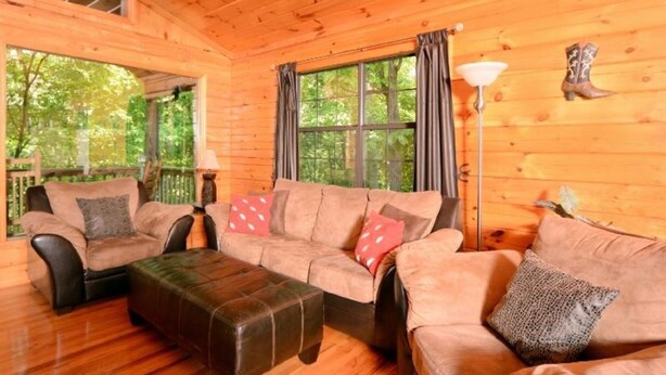 A cozy cabin interior with wooden walls, a sofa set, a coffee table, and a lamp. - 2 Min to Dollywood!  5 min To Pigeon Forge! Come check us out!!! (Sevierville)