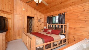 A wooden cabin bedroom with a bed, a nightstand, a TV, and a window with curtains. - 2 Min to Dollywood!  5 min To Pigeon Forge! Come check us out!!! (Sevierville)