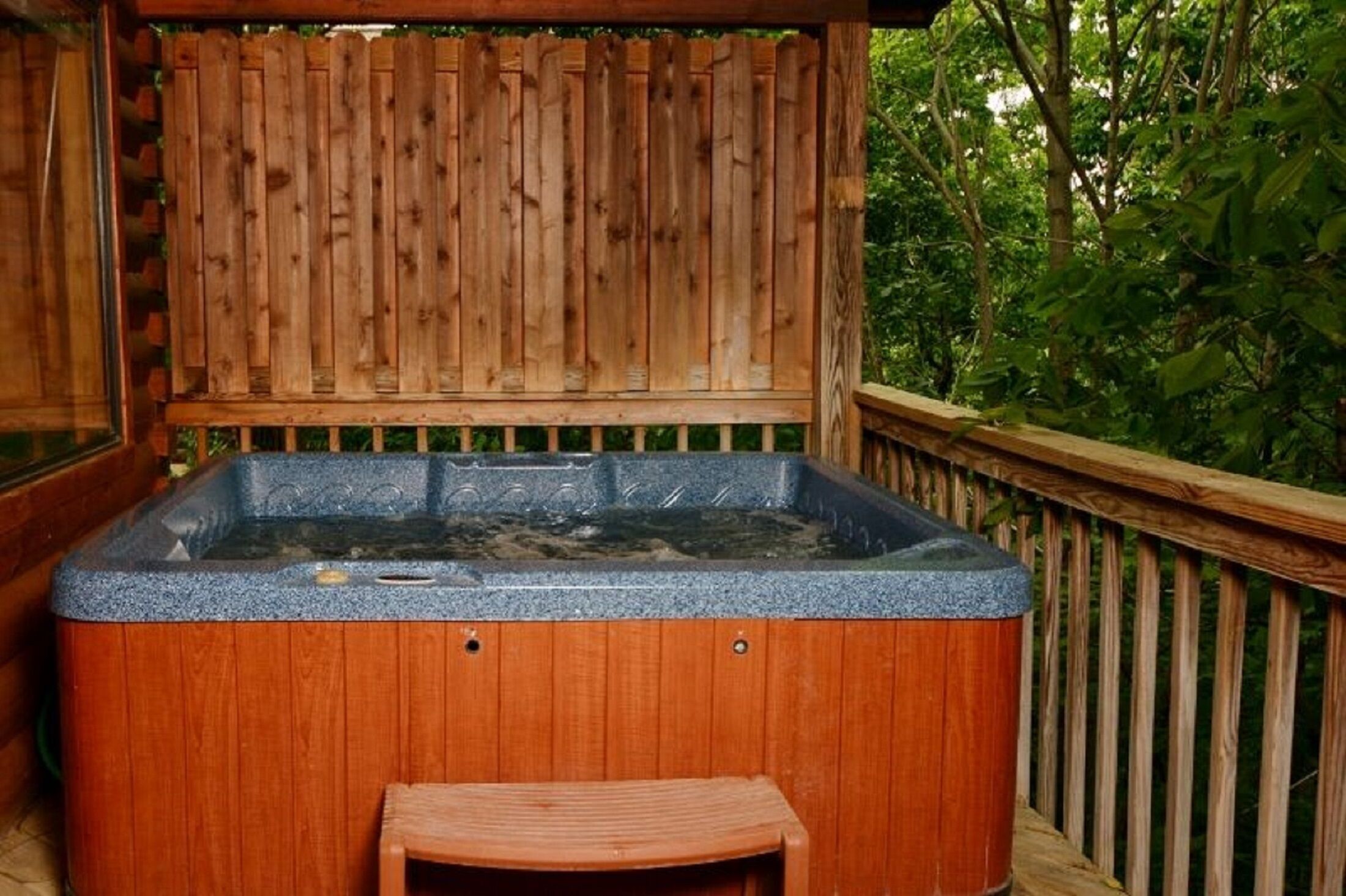 Un jacuzzi con terraza de madera y cerca de madera.