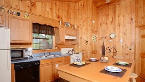 A wooden cabin kitchen with a central island, a microwave, a stove, and a sink. - 2 Min to Dollywood!  5 min To Pigeon Forge! Come check us out!!! (Sevierville)