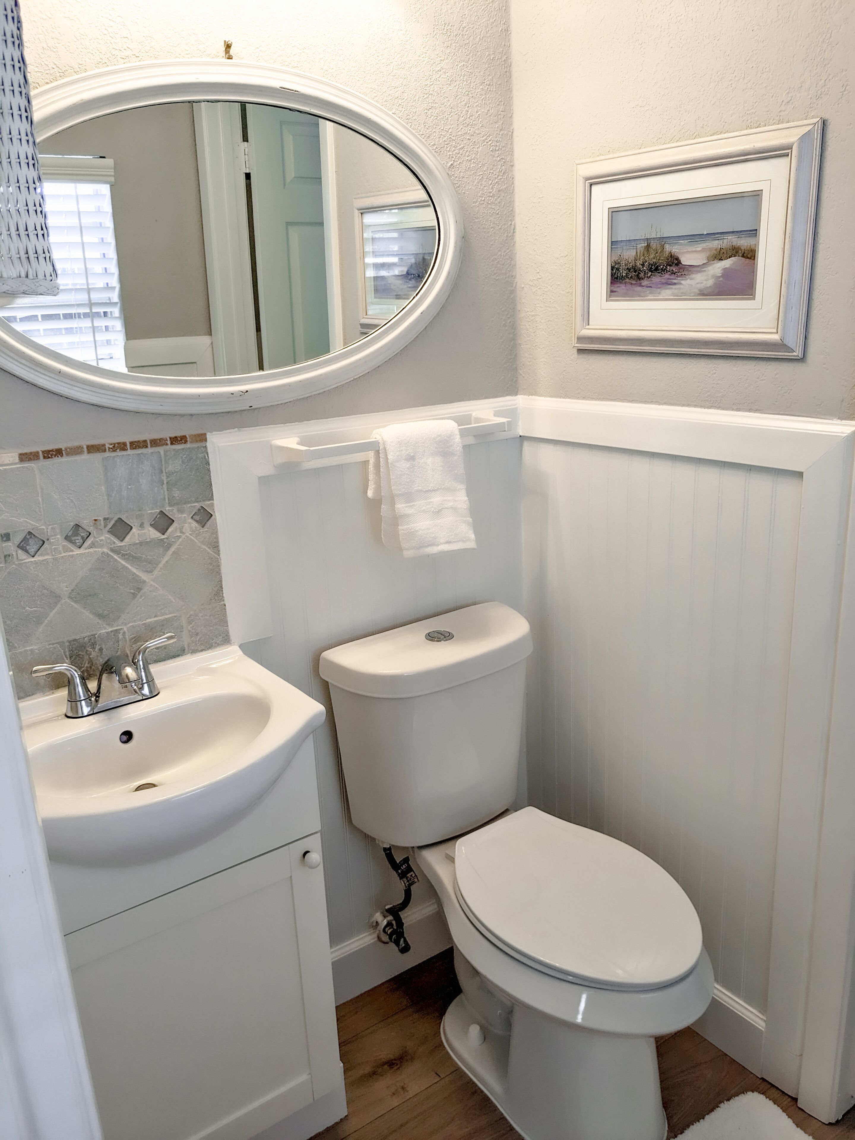 A bathroom with a white sink, toilet, and mirror.